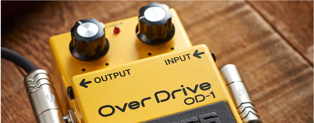 Close-up of a yellow OverDrive OD-1 guitar pedal with input and output jacks.