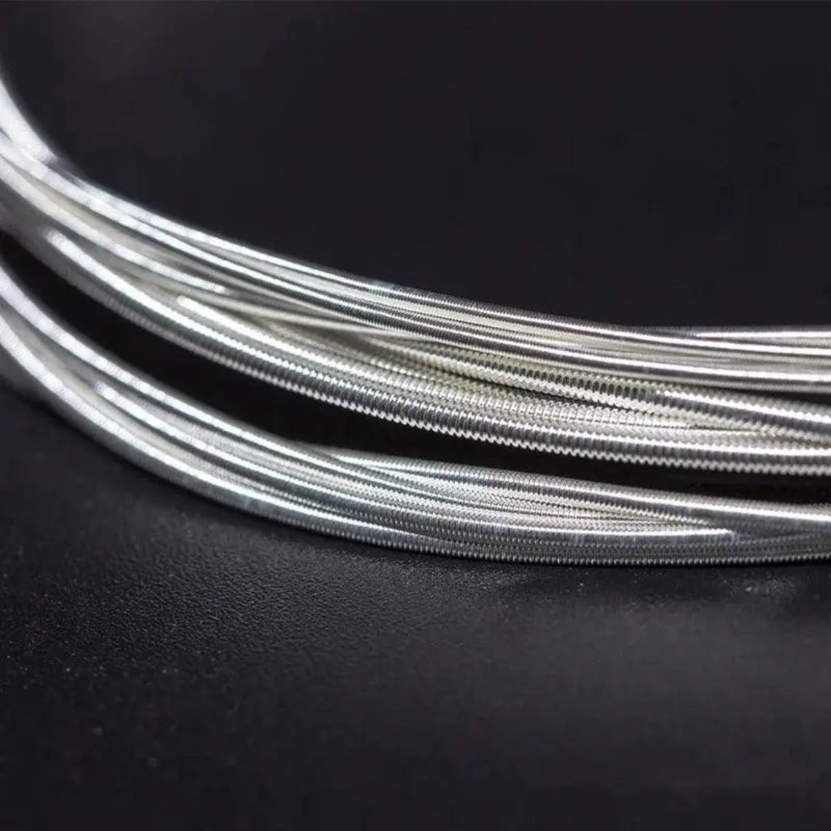 Close-up of Orphee NX35 classical guitar strings with a silver-wound design. These hard tension nylon-core strings provide rich tone and durability.